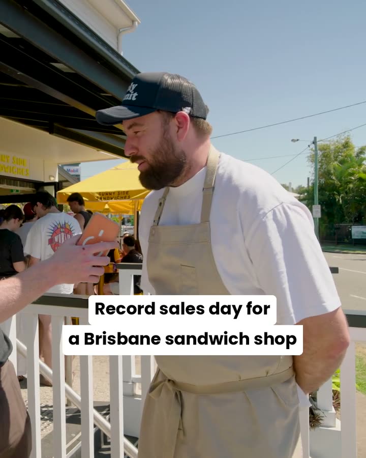 Mack Bowers, owner of Sunny Side Sandwiches, outside his shop with a queue behind him